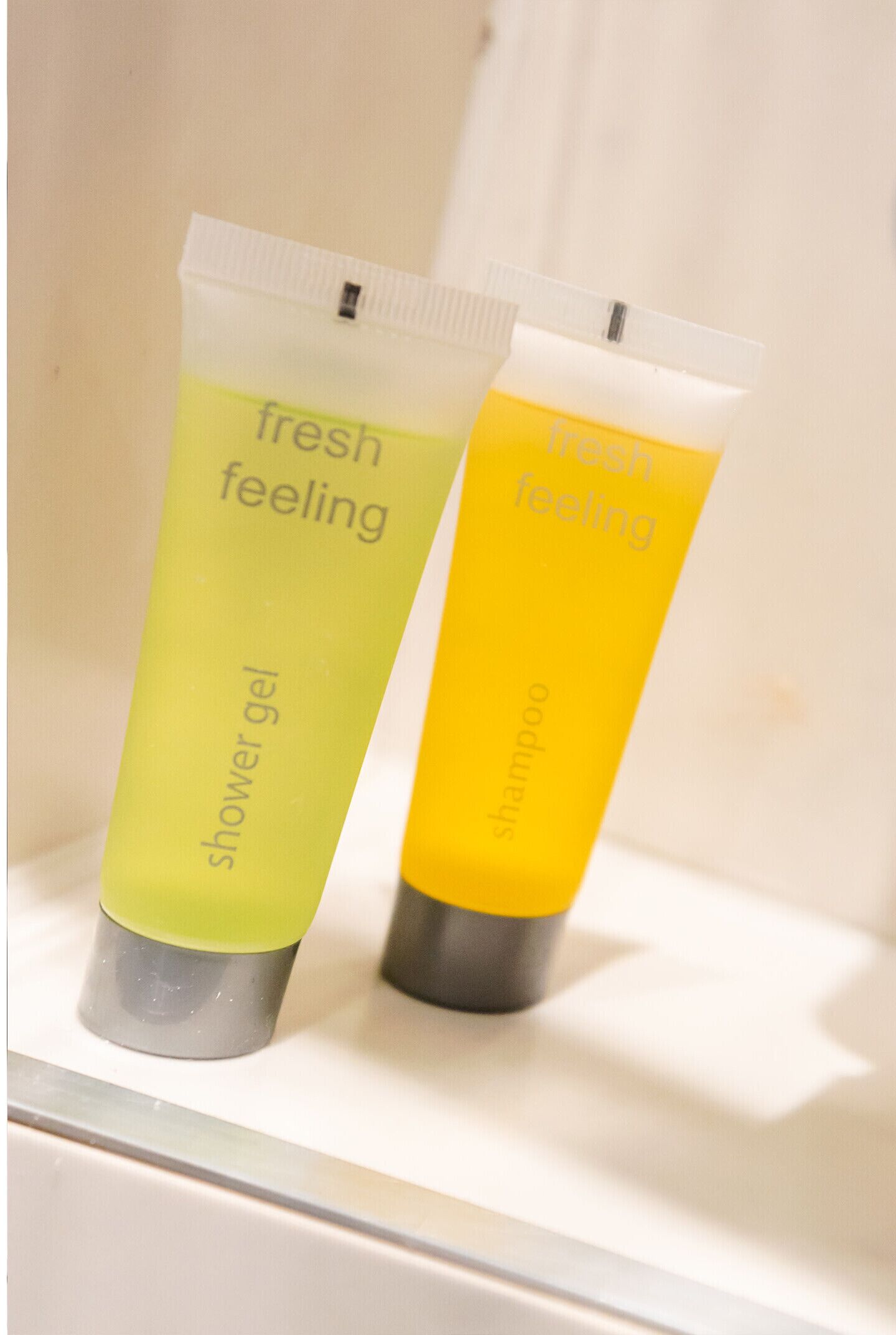 Two tubes of 'fresh feeling' shower gel and shampoo on a bathroom counter.