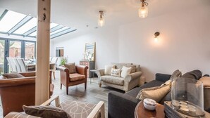 Un salon spacieux avec un plafond haut, une grande fenêtre et un coin salon confortable.