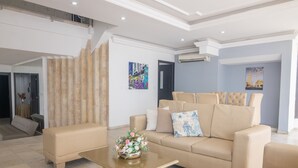 A modern living room with a beige sofa set, a coffee table with a floral centerpiece, and artwork on the walls.