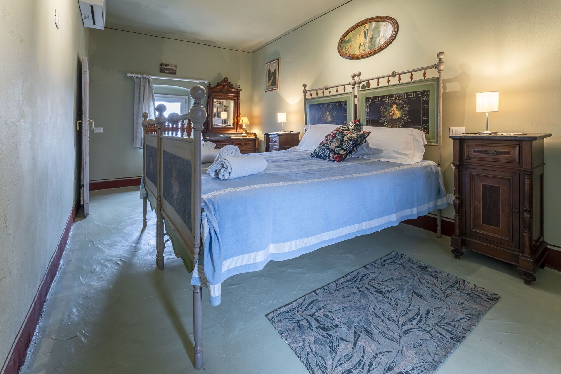 A bedroom with a four-poster bed, a wooden nightstand, a dresser, and a large mirror.