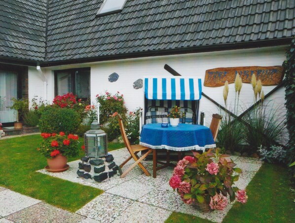 A patio with a table and chairs, surrounded by potted plants and flowers.