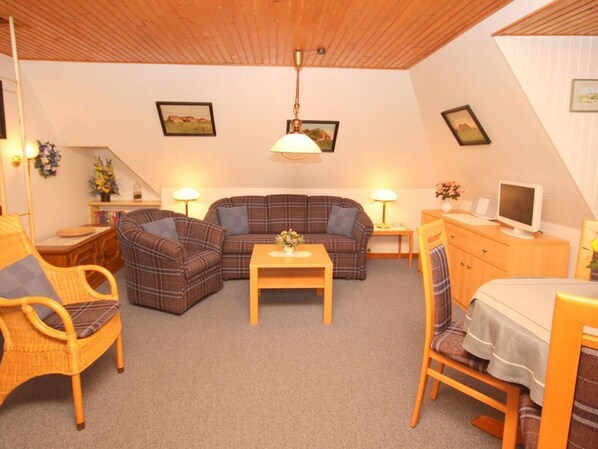 Una sala de estar acogedora con un sofá, sillones, una mesa de centro y un televisor.