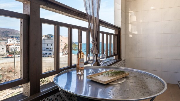 A balcony with a round table, a bottle of wine, and two glasses. - Geoje Blueberry Pet Pension (Geoje)