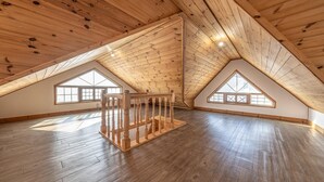 A spacious attic room with wooden slats on the ceiling, large windows, and a wooden staircase. - Geoje Blueberry Pet Pension (Geoje)