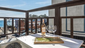 Ein Balkon mit Tisch, einer Weinflasche und zwei Gläsern.