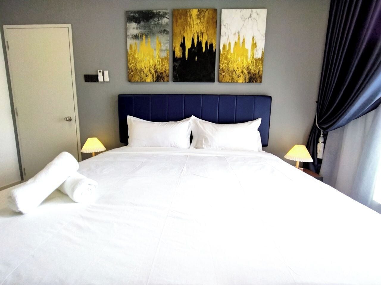 Une chambre d’hôtel avec un grand lit, deux lampes de chevet et trois tableaux au mur.