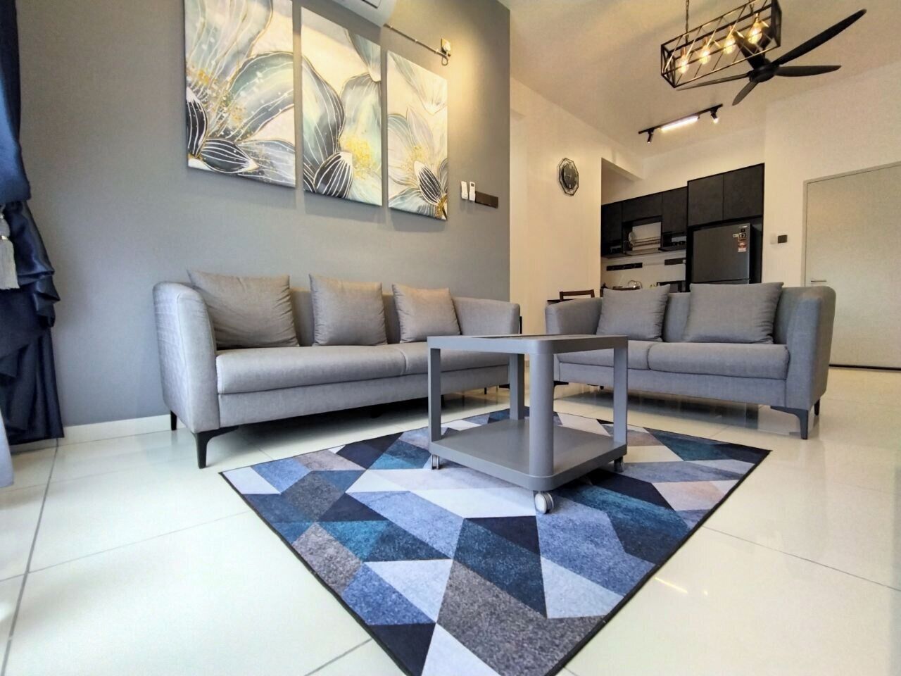 Uma sala de estar moderna com um sofá cinzento, uma mesa de centro e um tapete geométrico.