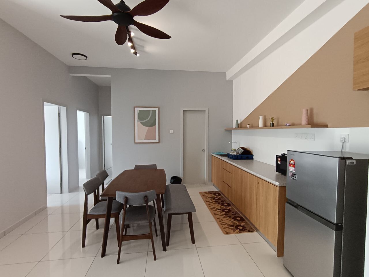 Una cocina moderna con refrigerador integrado, gabinetes de madera y un comedor con mesa y sillas.