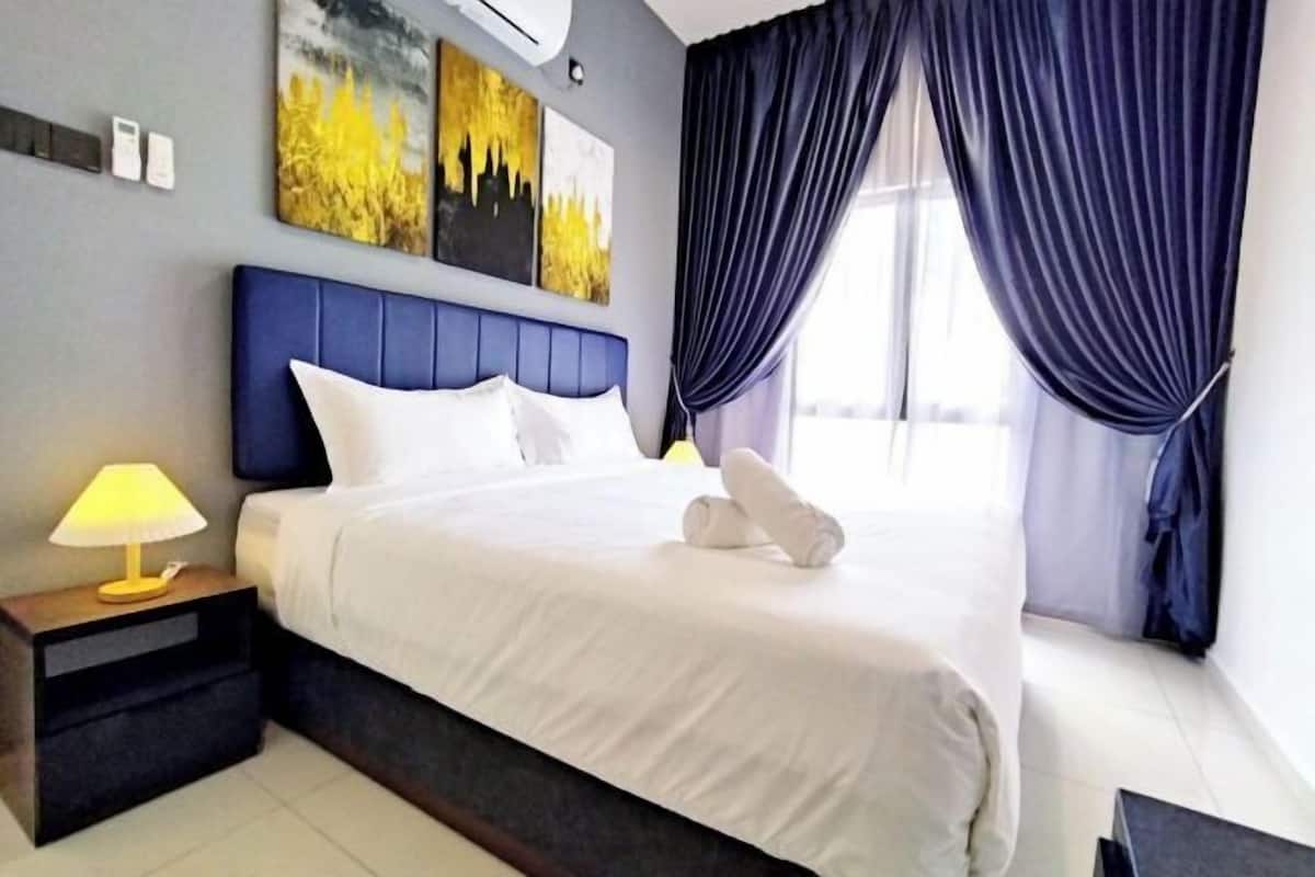 A hotel room with a bed, a nightstand with a lamp, and artwork on the wall.