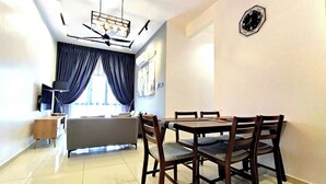 Un espace repas moderne avec une table ronde et des chaises en bois, un canapé et un téléviseur posé sur un meuble.