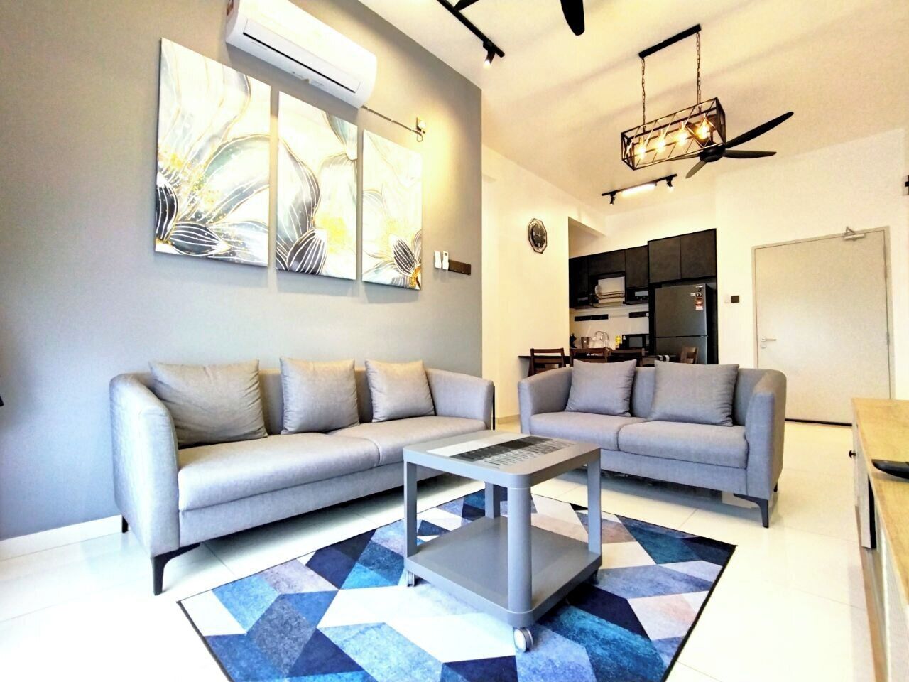 A modern living room with two grey sofas, a coffee table, and abstract wall art.