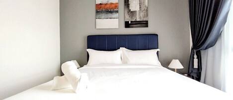 Una cama bien tendida con sábanas blancas, un cabecero azul y dos cuadros abstractos en la pared.