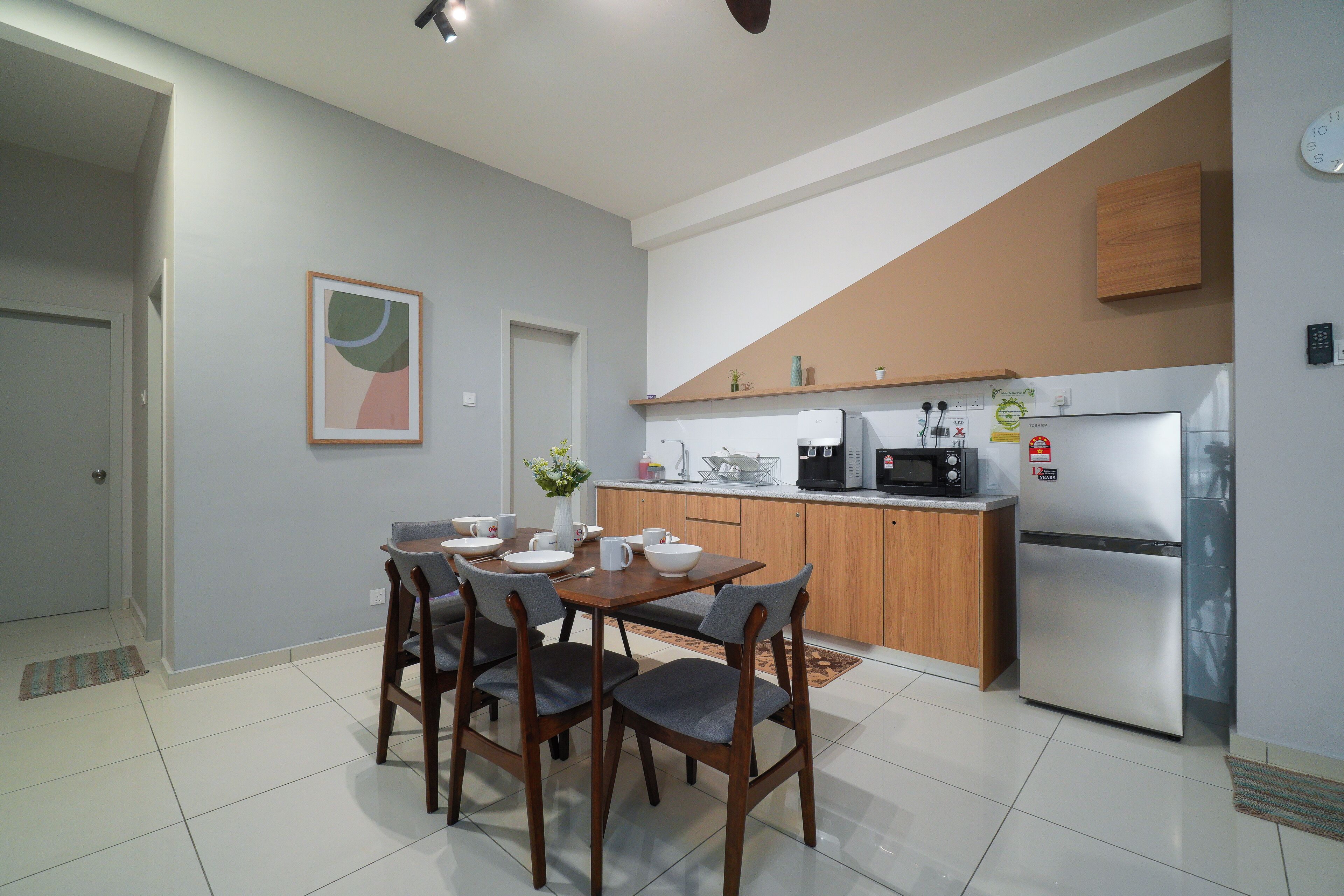 A modern kitchen with wooden cabinets, a stainless steel refrigerator, and a dining area with a table and chairs.