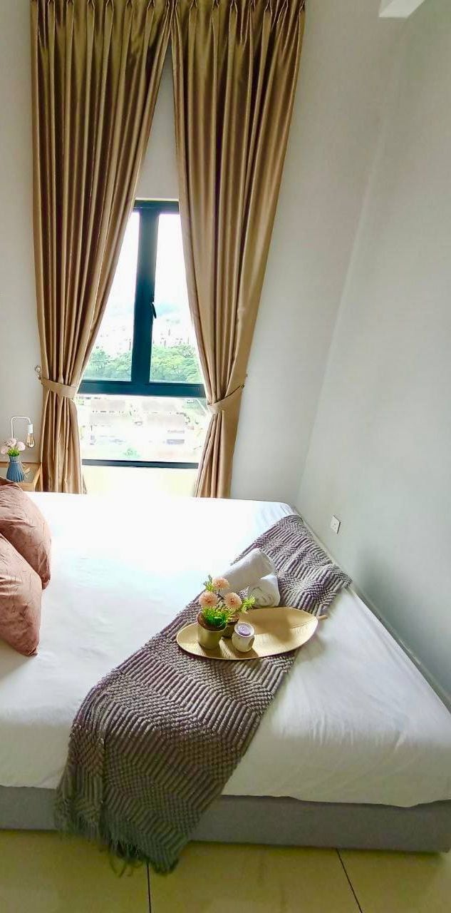 A bed with a tufted headboard, white bedding, and a decorative tray with a hat and flowers.