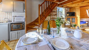 Een gezellig houten chalet van binnen met een eethoek, keuken en een wenteltrap.
