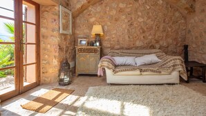 A cozy room with a stone wall, a wooden door, a sofa, a lamp, and a small cabinet. - SA TEULERA (FORNALUTX) - Fabulous house with stunning views of the Serra de Tramuntana - F (Fornalutx)