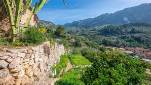 A stone wall with a cactus, a path, and a view of a valley with buildings and mountains. - SA TEULERA (FORNALUTX) - Fabulous house with stunning views of the Serra de Tramuntana - F (Fornalutx)