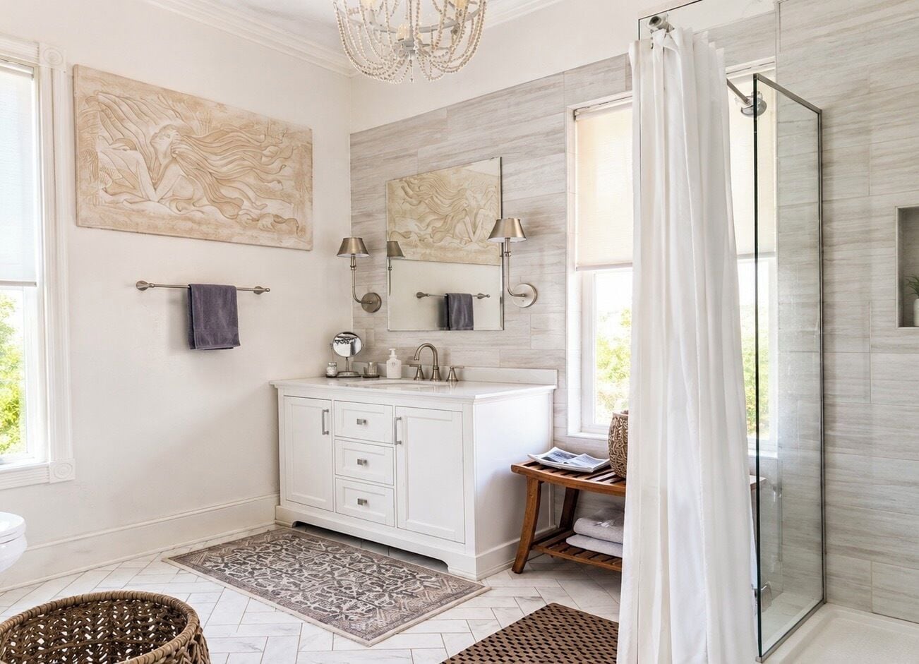 A modern bathroom with a white vanity, a glass shower enclosure, and artwork on the walls.