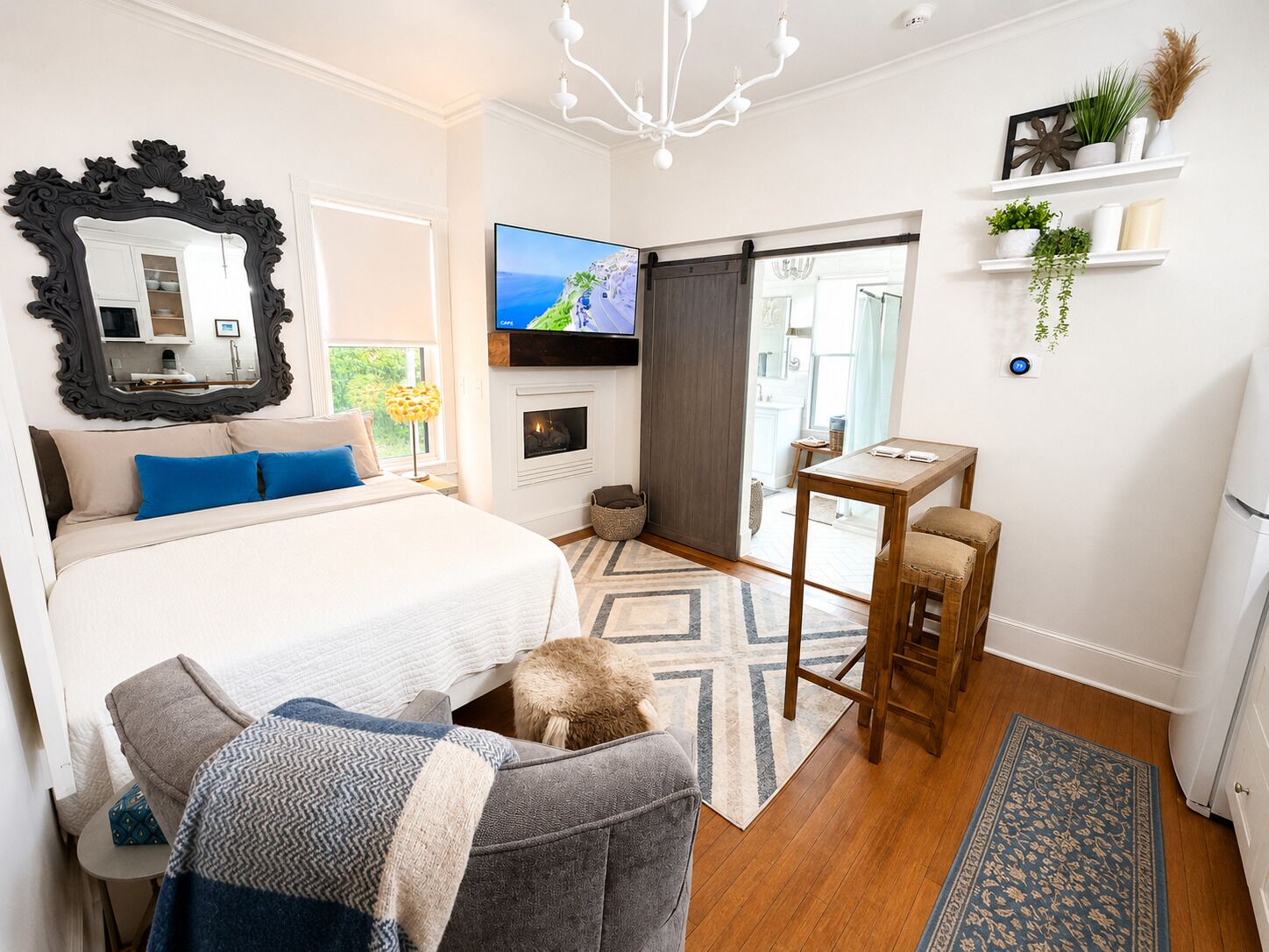 Un dormitorio moderno con una cama grande, televisor, chimenea y una mesita.