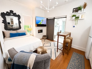 Una camera da letto moderna con un letto grande, una televisione, un caminetto e un tavolino.
