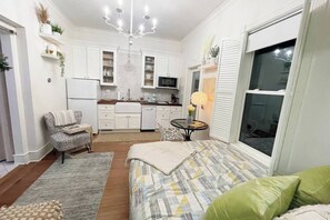 A compact, well-lit room with a kitchenette, a dining area, and a large window.