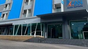 Een modern hotelgebouw met een opvallende blauwe gevel, meerdere balkons en een bord met de tekst 'KANN PATTAYA'.
