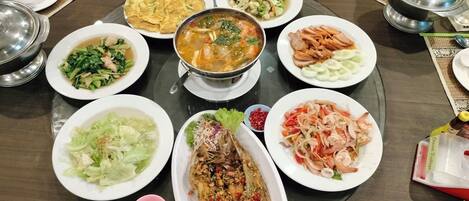 A round table with various dishes, including seafood, vegetables, and a soup.