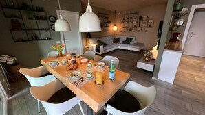 Een moderne keuken en eetruimte met een houten tafel, witte stoelen en hanglampen.