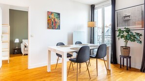 A modern dining area with a white table, dark chairs, and a potted plant.