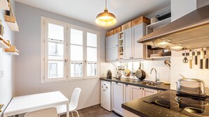 A modern kitchen with white cabinets, a black countertop, and a window with white frames.