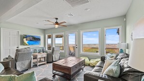 A spacious living room with a large window, a ceiling fan, and a view of the outdoors.
