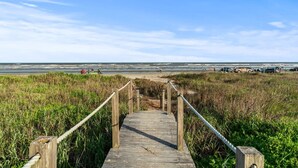 A wooden boardwalk leading to a beach with a clear sky.