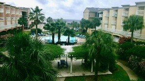 En hotelgård med swimmingpool, palmer og liggestole.