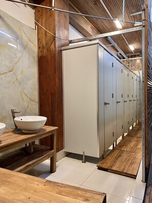 A bathroom with a marble wall, wooden bench, and a row of lockers. - the gk house (Ho Chi Minh City)