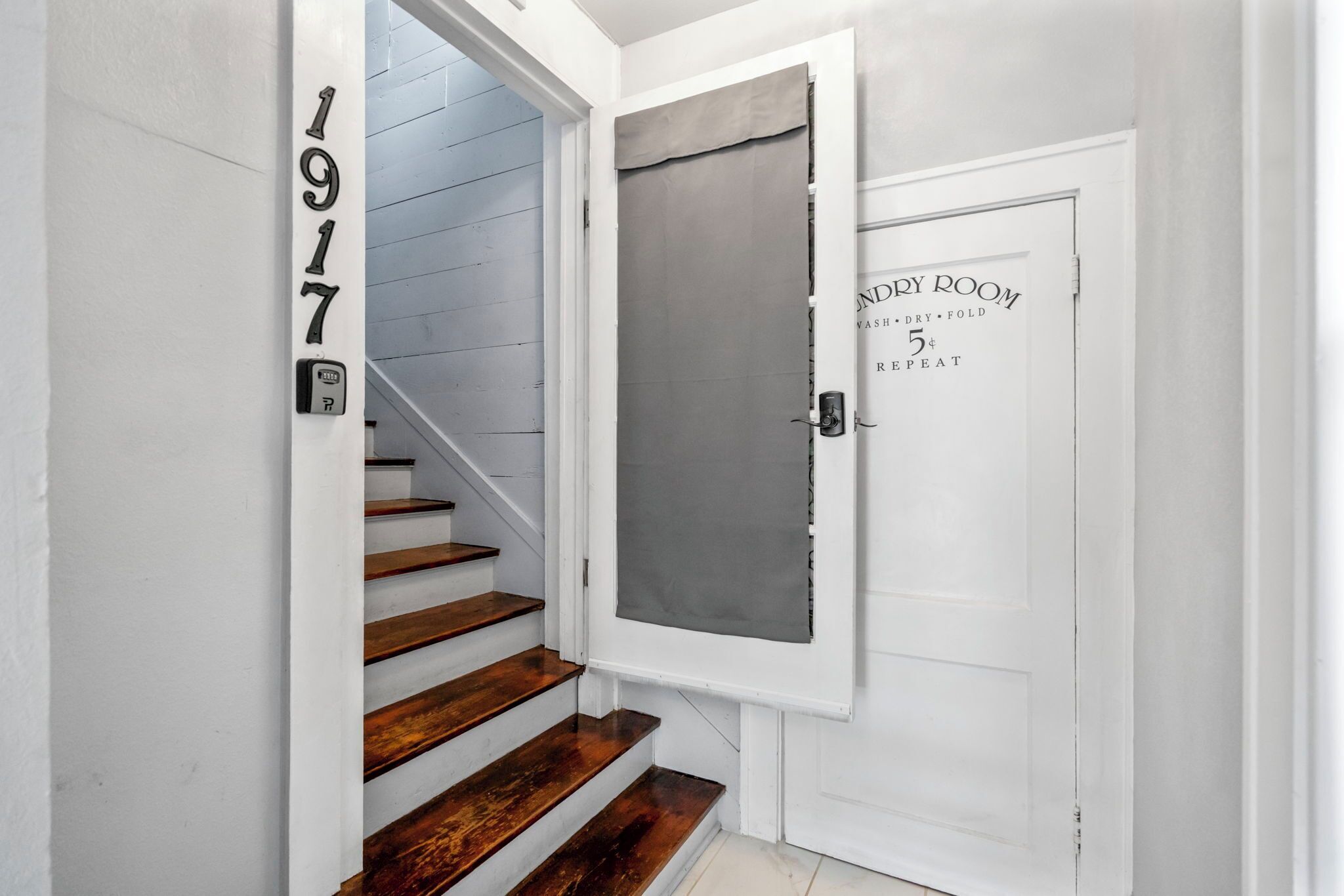 Eine Treppe mit Holzsstufen führt zu einer Tür mit der Aufschrift 'INDURY ROOM' und Gebrauchsanweisung.