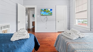 Een hotelkamer met twee bedden, een televisie aan de muur en uitzicht op het buiten.