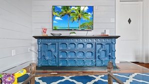Een blauwe kast met een televisie erboven, een tapijt met een patroon en een deur met een diamantvormige decoratie.