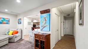 Un salon avec un canapé, une table basse et un meuble en bois. Il y a des tableaux accrochés aux murs et une enseigne au-dessus du meuble.