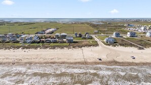 Luchtbeeld van een kustgebied met woningen, een strand en een weg.