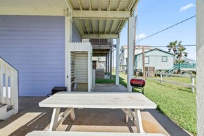Eine überdachte Veranda mit Picknicktisch und Grill.