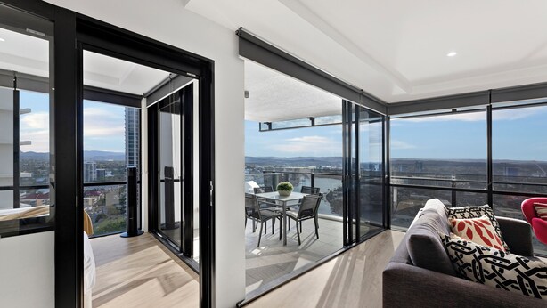 A modern apartment with a balcony, large windows, and a city view. - Circle on Cavill River View (Surfers Paradise)