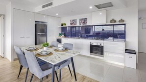 A modern kitchen with white cabinetry, a built-in stove, and a large window overlooking a cityscape. - Circle on Cavill River View (Surfers Paradise)