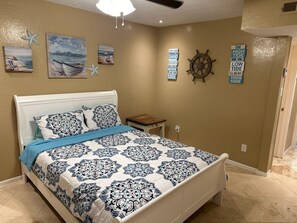 A bedroom with a bed, a nightstand, and wall decorations including a starfish, a boat, and a ship's wheel.