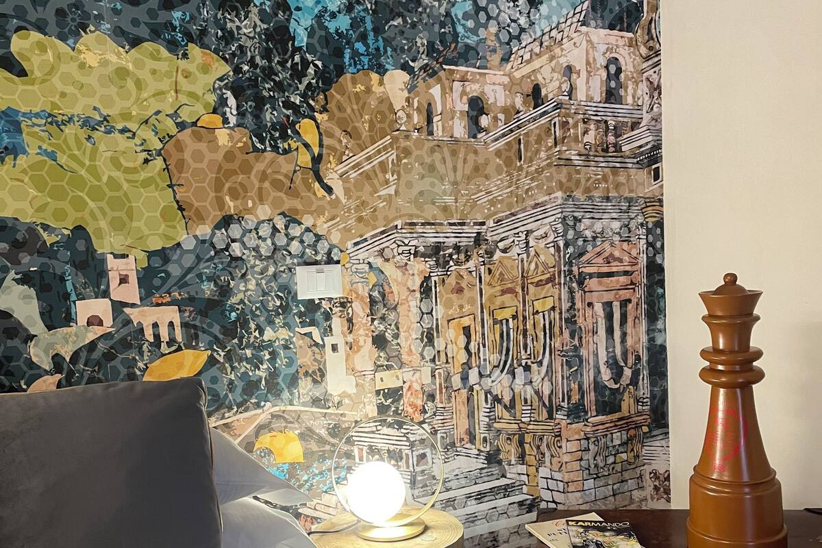 Ein Zimmer mit einem Bett, einer Lampe, einer Schachfigur und einer Wand mit einem Mosaik.