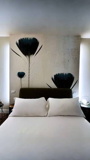 Une chambre d’hôtel moderne avec un grand lit, une œuvre d’art murale aux lignes épurées et une petite table de chevet.