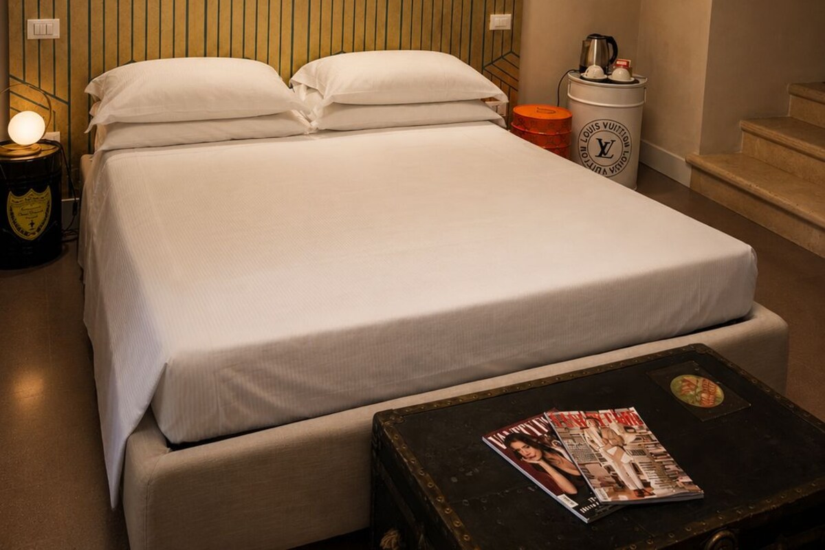 Une chambre d’hôtel avec un lit, une table de chevet, une lampe et un magazine sur une petite table.