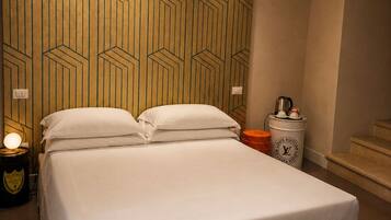 A hotel room with a bed, bedside table, lamp, and a magazine on a small table.