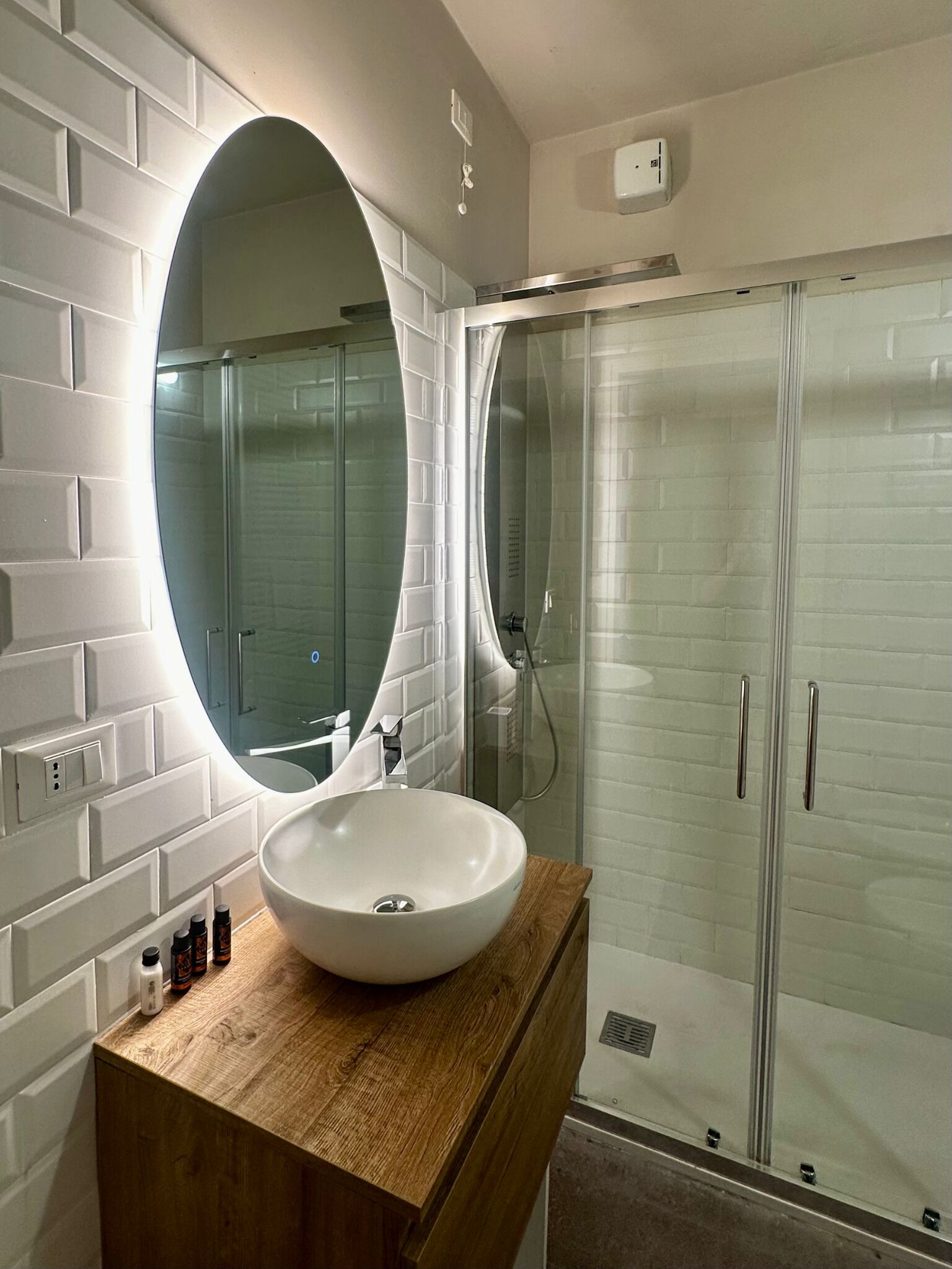A bathroom with a white sink, wooden vanity, and a large mirror.