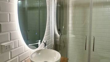 A bathroom with a white sink, wooden vanity, and a large mirror.