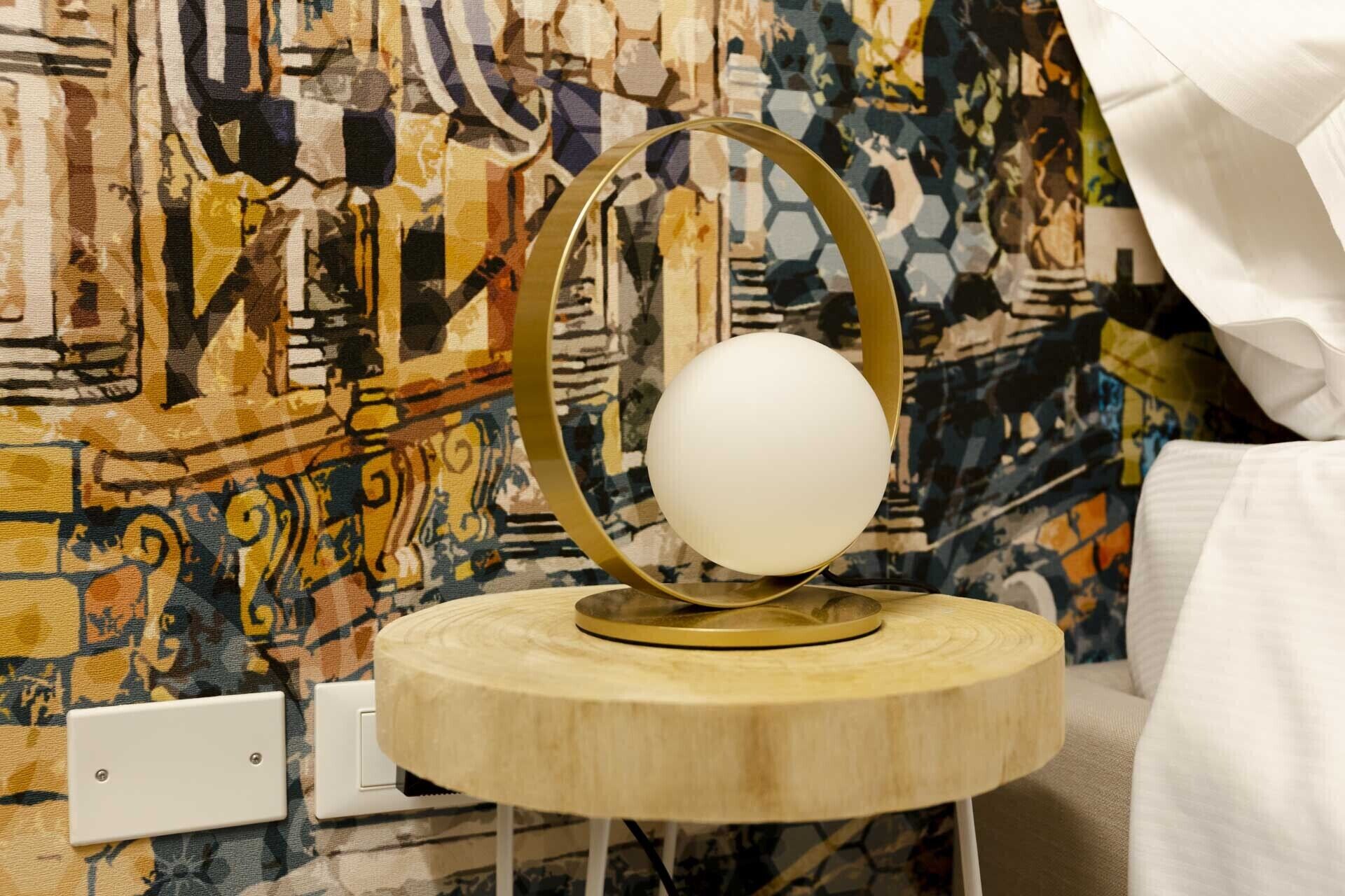 A round table with a white spherical object on top, set against a colorful abstract wall.